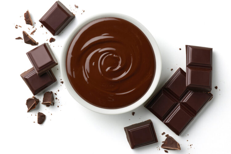 Bowl of melted dark chocolate and broken pieces of chocolate bar isolated on white background, top view